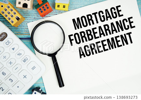Notepad with "Mortgage Forbearance Agreement" with Calculator, magnifying glass and house model on wooden background Notepad with "Mortgage Forbearance Agreement" with Calculator, magnifying glass and house model on wooden background 138693273