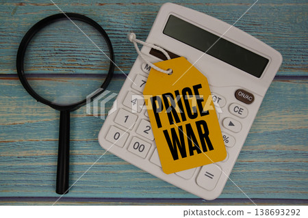 Price tag with "PRICE WAR" on calculator and magnifying glass on a rustic blue wooden surface Price tag with "PRICE WAR" on calculator and magnifying glass on a rustic blue wooden surface 138693292