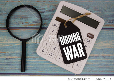 Price tag with "BIDDING WAR" on calculator and magnifying glass on a rustic blue wooden surface Price tag with "BIDDING WAR" on calculator and magnifying glass on a rustic blue wooden surface 138693293