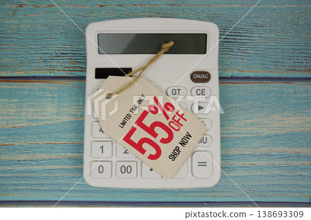 Sale 55% off Shop Now with price tag and calculator on wooden background Sale 55% off Shop Now with price tag and calculator on wooden background 138693309