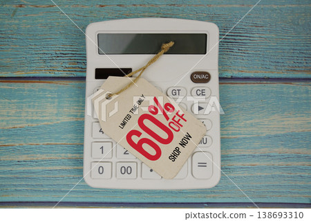 Sale 60% off Shop Now with price tag and calculator on wooden background Sale 60% off Shop Now with price tag and calculator on wooden background 138693310
