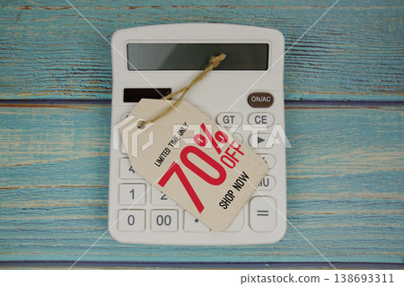 Sale 70% off Shop Now with price tag and calculator on wooden background Sale 70% off Shop Now with price tag and calculator on wooden background 138693311