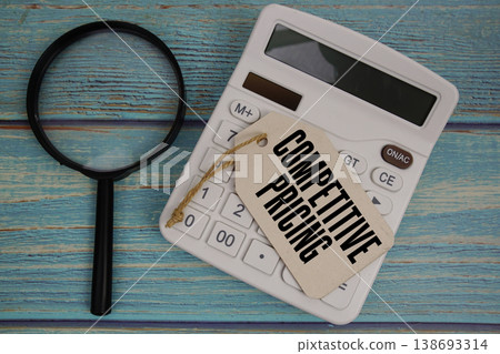 Price tag with "COMPETITIVE PRICING" on calculator and magnifying glass on a rustic blue wooden surface Price tag with "COMPETITIVE PRICING" on calculator and magnifying glass on a rustic blue wooden surface 138693314
