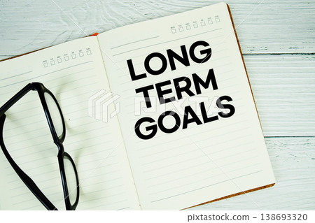 Notepad with message "Long Term Goals" and eyeglass on wooden background 138693320