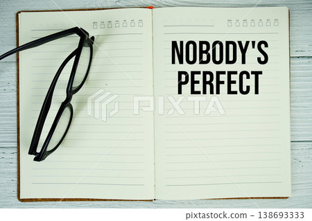 Notepad with message "Nobody's Perfect" and eyeglass on wooden background Notepad with message "Nobody's Perfect" and eyeglass on wooden background 138693333