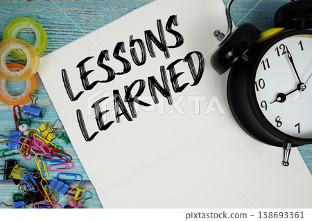 Lessons Learned text with alarm clock and colorful office supplies on a blue wooden surface Lessons Learned text with alarm clock and colorful office supplies on a blue wooden surface 138693361