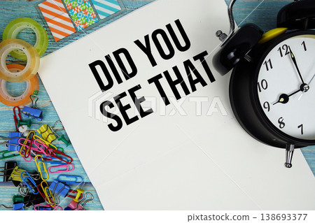 Did You See That text with alarm clock and colorful office supplies on a blue wooden surface 138693377