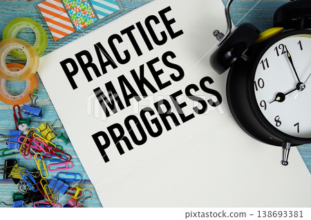 Practice Makes Progress text with alarm clock and colorful office supplies on a blue wooden surface Practice Makes Progress text with alarm clock and colorful office supplies on a blue wooden surface 138693381