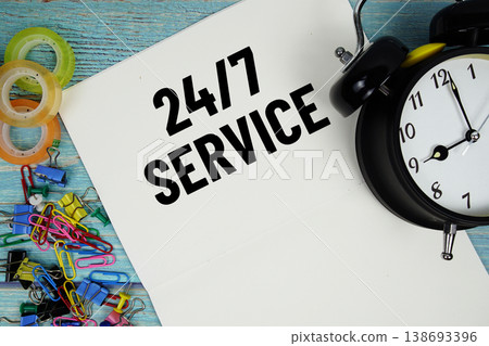 247 Service text with alarm clock and colorful office supplies on a blue wooden surface 138693396