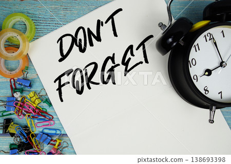 Don't Forget text with alarm clock and colorful office supplies on a blue wooden surface Don't Forget text with alarm clock and colorful office supplies on a blue wooden surface 138693398