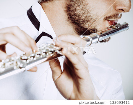 Male flutist playing his flute closeup 138693411