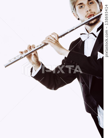 Male flutist wearing tailcoat plays flute Male flutist wearing tailcoat plays flute 138693414