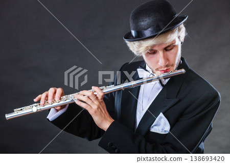 Elegantly dressed male musician playing flute 138693420