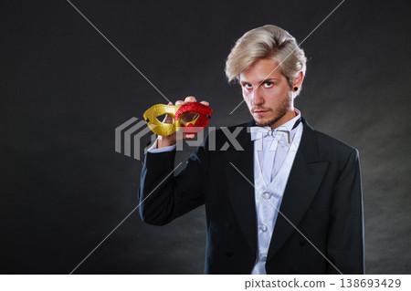 Young man in carnival mask on dark Young man in carnival mask on dark 138693429