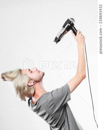 Young man drying hair with hairdryer Young man drying hair with hairdryer 138693432