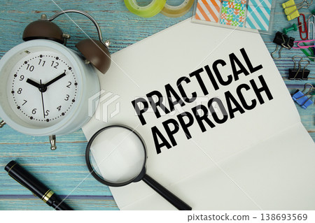 Practical Approach text on a paper surrounded by office supplies, a magnifying glass, and a clock on a blue wooden surface Practical Approach text on a paper surrounded by office supplies, a magnifying glass, and a clock on a blue wooden surface 138693569