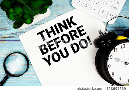 Think Before You Do! written on paper placed on a blue wooden surface, alongside a magnifying glass, a clock, a calculator, and a small plant 138693589