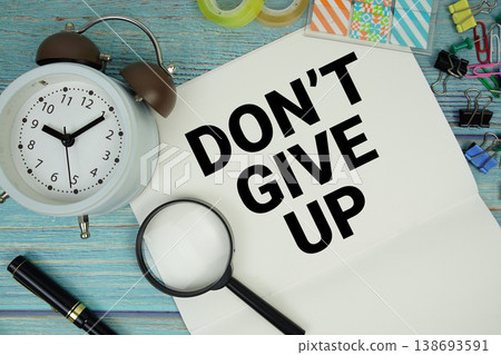 Don't Give Up text written on notepad with alarm clock and magnifying glass flat lay on wooden background Don't Give Up text written on notepad with alarm clock and magnifying glass flat lay on wooden background 138693591