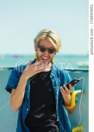 Blonde man outside using his smartphone Blonde man outside using his smartphone 138693601