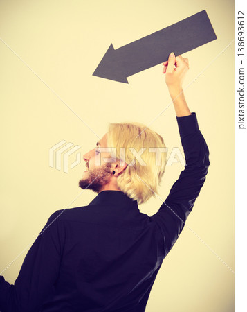 Man holding black arrow pointing left down Man holding black arrow pointing left down 138693612