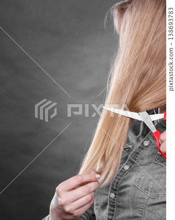 Blonde woman cutting her hair. 138693783