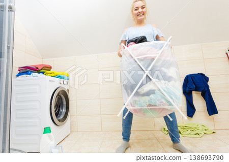 Woman carry big basket of dirty clothes laundry. 138693790