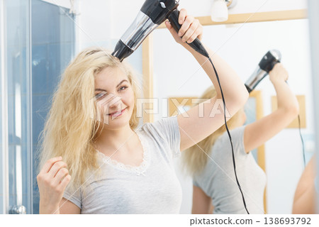 Blonde woman using hair dryer Blonde woman using hair dryer 138693792