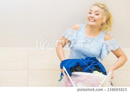 Woman holding laundry basket full of clothes Woman holding laundry basket full of clothes 138693823