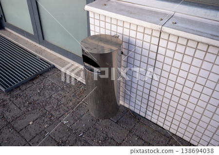 Metal outdoor trash bin near tiled wall urban public waste management concept 138694038