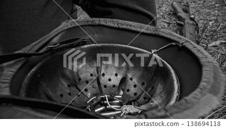 Inverted German steel helmet with ammunition cartridges inside on ground 138694118