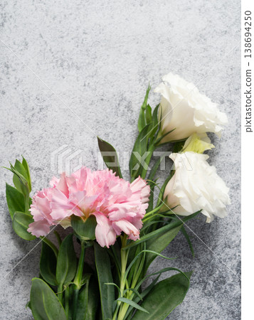 Fresh pink carnations and white eustomas on a gray concrete background, top view. Fresh pink carnations and white eustomas on a gray concrete background, top view. 138694250