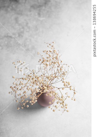 A dried bouquet of gypsophila flowers in a soft pink vase on a concrete background A dried bouquet of gypsophila flowers in a soft pink vase on a concrete background 138694255