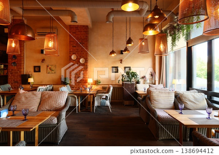 Industrial styled cafe featuring inviting seating and warm accents 138694412