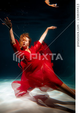 Caucasian woman wearing red attire reaches toward top of blue pool 138694413