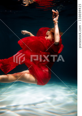 Underwater shot showing woman in red dress with strong contrast 138694415