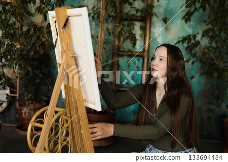 Young woman creates art amid indoor greenery and sunlight 138694484