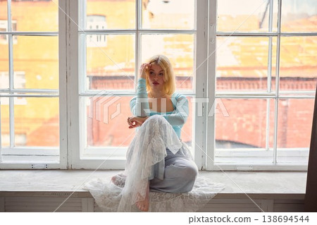 Calm woman seated by window capturing urban environment atmosphere 138694544
