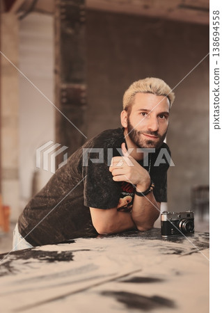 Sunkissed Caucasian male in introspective pose with camera on ground 138694558