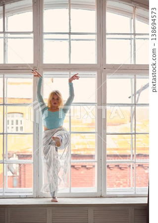Studio scene showing woman confidently posing on windowsill Studio scene showing woman confidently posing on windowsill 138694573