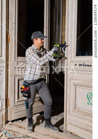 Expert operator using grinding tool to restore ornate doorframe safely Expert operator using grinding tool to restore ornate doorframe safely 138694574