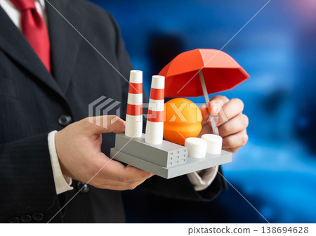 A businessman holds an umbrella over an industrial factory. Insurance and protection of industry and business. Risk management safeguards assets and ensures stability in uncertain conditions. A businessman holds an umbrella over an industrial factory. Insurance and protection of industry and business. Risk management safeguards assets and ensures stability in uncertain conditions. 138694628