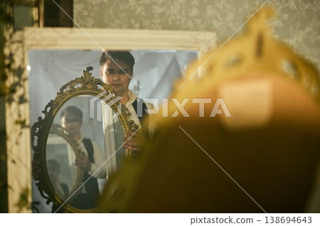 Performer framing face with ornate mirror, layered reflection Performer framing face with ornate mirror, layered reflection 138694643