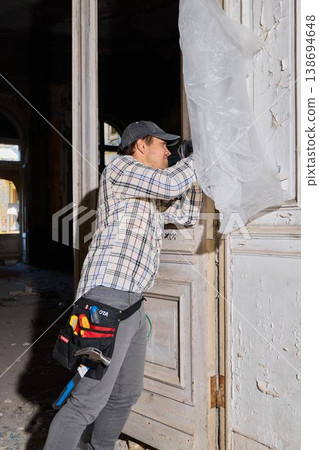 Worker restoring decorated doorway amidst dust particles 138694648