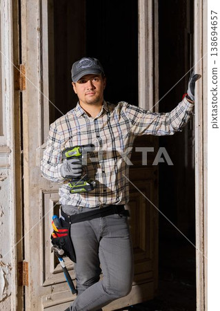 Confident contractor taking project pause leaning on doorframe Confident contractor taking project pause leaning on doorframe 138694657