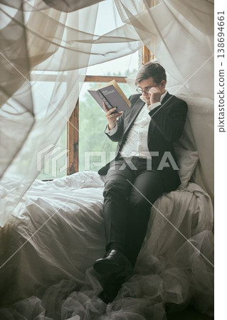 Someone dressed formally finds solace in peaceful reading by window 138694661