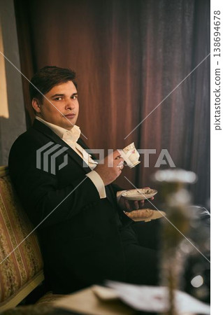 Man drinks tea. Elegant gentleman in vintage setting savoring his tea Man drinks tea. Elegant gentleman in vintage setting savoring his tea 138694678