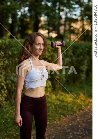 Active young woman performing lateral raise during exercise session Active young woman performing lateral raise during exercise session 138694710