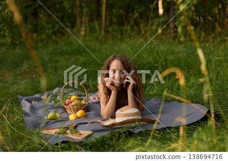Female enjoying picnic, Lady resting outdoors amid picnic setting Female enjoying picnic, Lady resting outdoors amid picnic setting 138694716