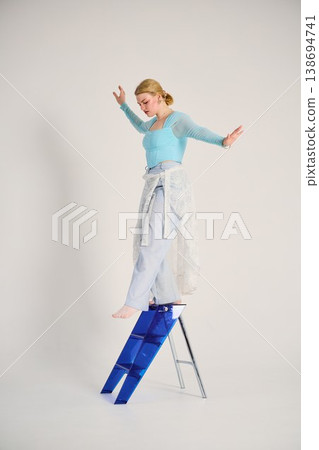Female dancer exploring movement barefoot alongside bright studio ladder Female dancer exploring movement barefoot alongside bright studio ladder 138694741