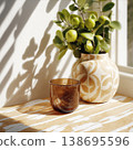 Ceramic Vase with Green Foliage on Sunlit Table 138695596